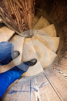 Men`s legs go down a wooden staircase