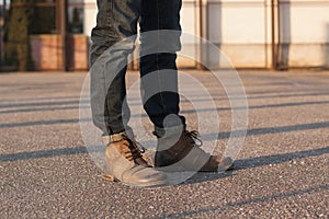 Men`s legs with jeans and boots. Hipster at sunset.