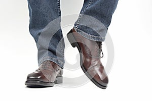 Men`s legs in jeans shod in classic brown Oxford shoes