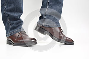Men`s legs in jeans shod in classic brown Oxford shoes
