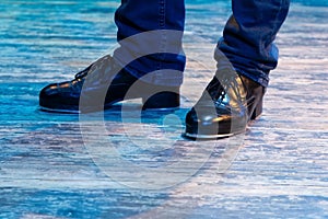 Men's legs in motion in stage trousers with stripes and leather shoes for Irish dancing on the floor