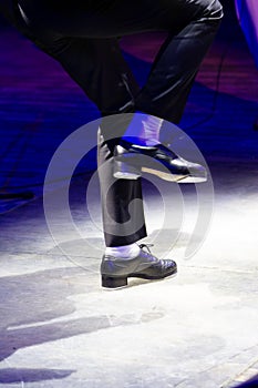 Men\'s legs in motion in stage trousers with stripes and leather shoes for Irish dancing on the floor