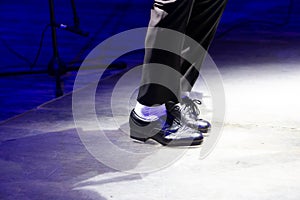 Men's legs in motion in stage trousers with stripes and leather shoes for Irish dancing on the floor