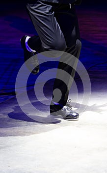 Men's legs in motion in stage trousers with stripes and leather shoes for Irish dancing on the floor