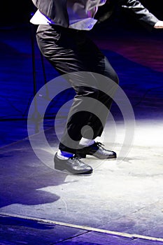 Men's legs in motion in stage trousers with stripes and leather shoes for Irish dancing on the floor