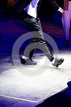 Men's legs in motion in stage trousers with stripes and leather shoes for Irish dancing on the floor