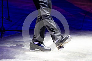 Men's legs in motion in stage trousers with stripes and leather shoes for Irish dancing on the floor