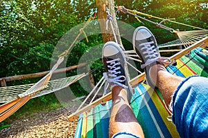 Men`s legs in sneakers in a hammock. Close-up. Summer concept, outdoor recreation