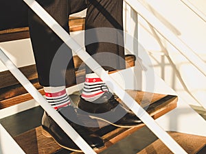 Men`s legs in stylish, black shoes, dark pants and funny, bright, striped socks