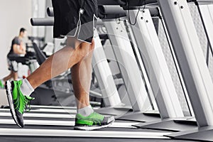 Men`s muscular legs on a treadmill close-up