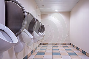 Men`s public restroom with urinals on the wall and checkered floor.