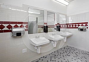 The sinks in a clean, tiled, modern Men`s room.