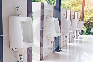Men`s room with white porcelain urinals in line. public Old bathroom
