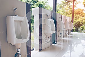 Men`s room with white porcelain urinals in line. public Old bathroom