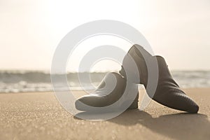 Men`s shoes on the beach at sunset.