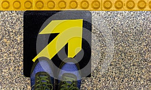 Men`s shoes on a yellow guidepost on a concrete floor. The concept of a decision made in accordance with our guidelines