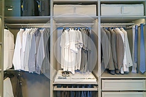 Men\'s suits and shirts hang in the closet