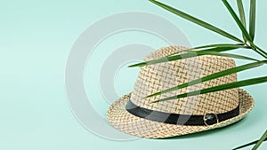 Men`s summer hat on a blue background under the leaves of a palm tree