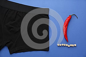Men`s underwear, chili pepper and word Impotency on blue background, flat lay photo