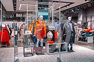 Men's and women's clothing store. Mannequins dressed in bright winter stylish women's clothing in a mall