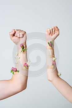 Men`s and women`s fist raised up as feminism symbol with medical patches and flowers. Concept poster for feminist blog