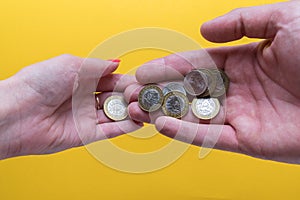 Men`s and women`s palms with coins. The man passes the coins to the woman. Lack of money. Family budget