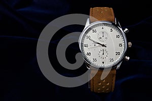 Men`s wrist watch with brown leather strap closeup on a dark blue background with place for your text