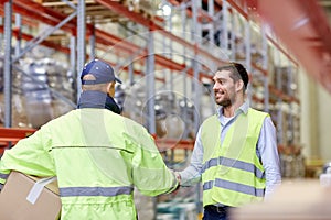 Men in safety vests shaking hands at warehouse