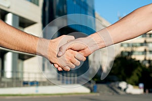 Men shaking hands on building background