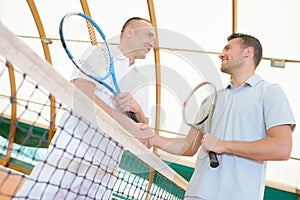 Men shaking hands over tennis court net