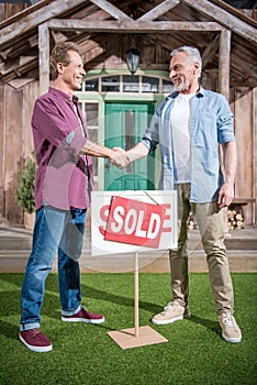 Men shaking hands with saleman and buying house photo