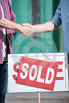 Men shaking hands with saleman and buying new house photo