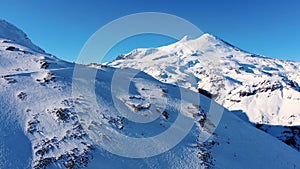 Men silhouettes ski on snowy mountain slope under blue sky