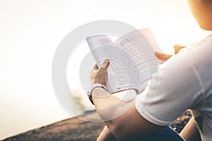 Men sit reading book in quiet nature.