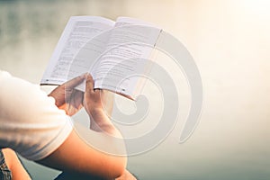 Men sit reading book in quiet nature.