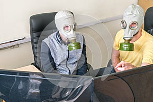 Men are sitting in an armchair and looking at computer monitors in protective masks. Two guys in gas masks are talking among