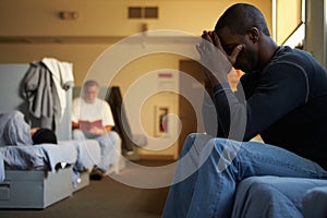 Men Sitting On Beds In Homeless Shelter