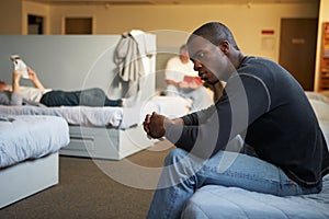 Men Sitting On Beds In Homeless Shelter