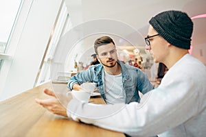 Men are sitting in front of the table near window