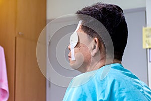Men sitting and use eye shield protection after eye surgery in the hospital room
