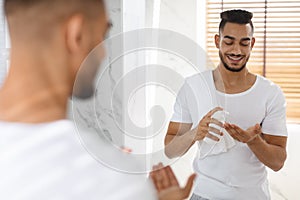 Men Skincare. Handsome Young Arab Man Using Aftershave Lotion In Bathroom