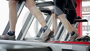 Men with skinny legs jogging on exercise machine in gym, running on treadmill