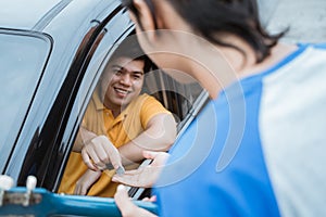 the man smiling from inside the car giving coin by hand from the car window to buskers photo
