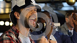 Men with soccer hat and vuvuzela cheering for favorite team victory in pub, fans