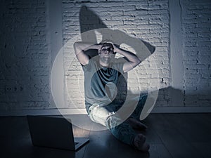 Men suffering Internet cyber bullying sitting alone with computer feeling hopeless