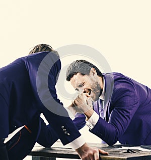 Men in suit or businessmen with screaming face compete in armwrestling on table on white background. Winner and defeated