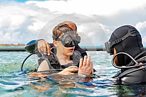 A man in a suit for diving prepares a boy to dive