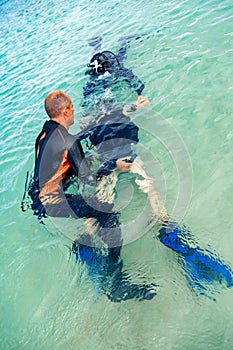 A man in a suit for diving prepares a boy to dive