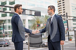 Men in suits handover briefcase outdoor. Business deal. Two business man hold business briefcase. Business transfer deal