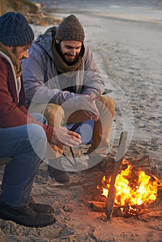 Men, sunset and campfire with cold hands, smile and happy from travel adventure and journey outdoor. Friends, ocean and